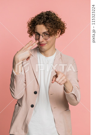 Young man pointing at eyes and camera show I am watching you gesture spying, watching on someone 115323224