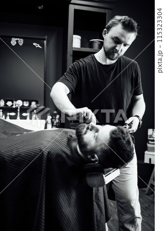 A man is getting his hair cut by another man 115323304