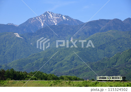 残雪の甲斐駒ヶ岳と小海線ローカル列車 115324502