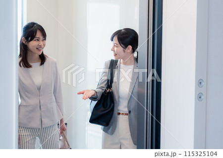 エレベーターで譲り合う2人のビジネスパーソン エレベーターで譲り合う2人のビジネスパーソン 115325104