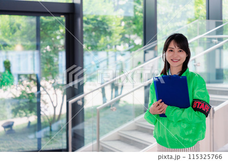 笑顔で案内をするイベントスタッフ 115325766