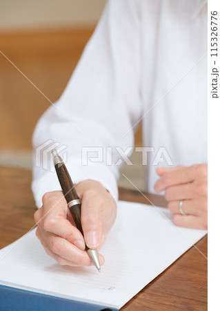 リビングで家族へ手紙を書くミドル女性 115326776