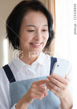 リビングでスマホを操作するミドル女性 リビングでスマホを操作するミドル女性 115326830