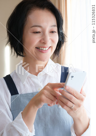 リビングでスマホを操作するミドル女性 リビングでスマホを操作するミドル女性 115326831