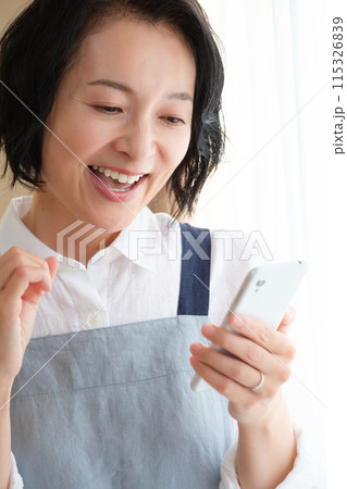 リビングでスマホを操作するミドル女性 115326839