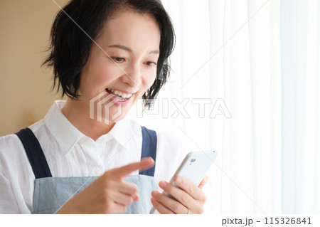 リビングでスマホを操作するミドル女性 リビングでスマホを操作するミドル女性 115326841