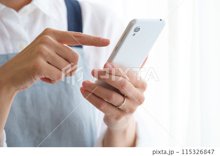 リビングでスマホを操作するミドル女性 リビングでスマホを操作するミドル女性 115326847
