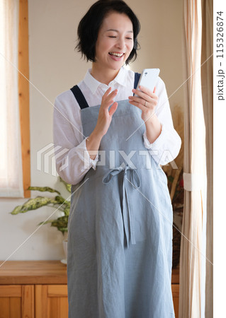 リビングでスマホを操作するミドル女性 リビングでスマホを操作するミドル女性 115326874