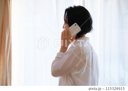 リビングで家族に電話をするミドル女性 115326915