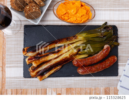 Catalan roasted calcots with salvitxada sauce and grilled botifarra 115328625