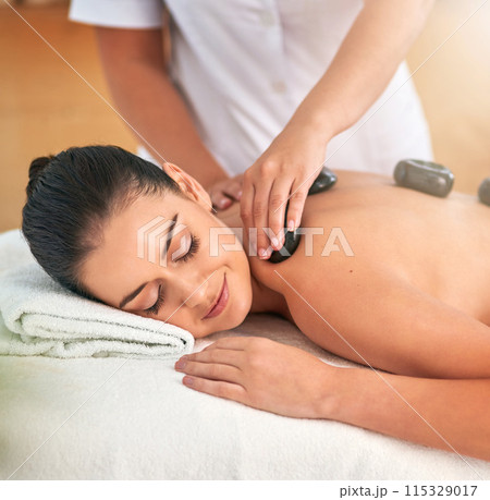 Face, hands for stone massage and woman in spa with masseuse to relax for health, peace or wellness. Beauty, calm or healing with client and therapist in clinic or salon for stress relief treatment 115329017