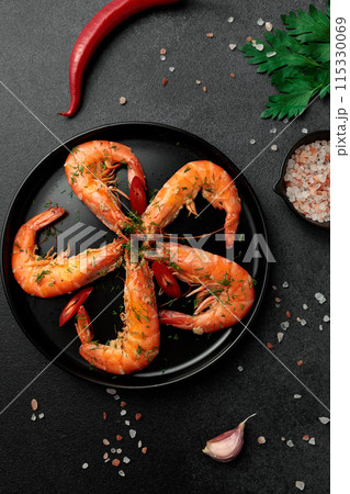 Large cooked king prawns on a black background. Lemon slices 115330069