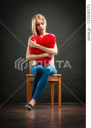 Sad unhappy woman holding red heart pillow 115330571