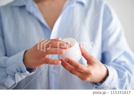 Hands in a blue shirt hold a jar of cream. Hands in a blue shirt hold a jar of cream. 115331817