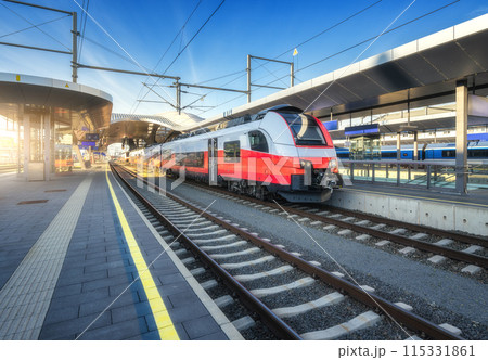 High-speed red passenger train at railway station at sunset High-speed red passenger train at railway station at sunset 115331861