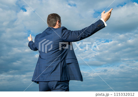 Professional man back view sky background. Man spreading arms wide open. Man in suit outdoors 115332012