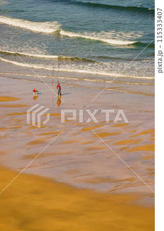 Angler with fishing rod on sea shore 115333407