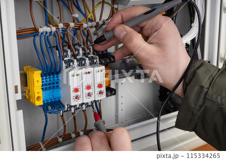 Electrician Working on Circuit Breaker Panel 115334265