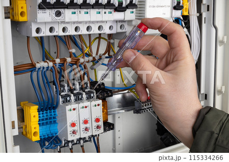 Technician Using Voltage Tester on Wiring 115334266
