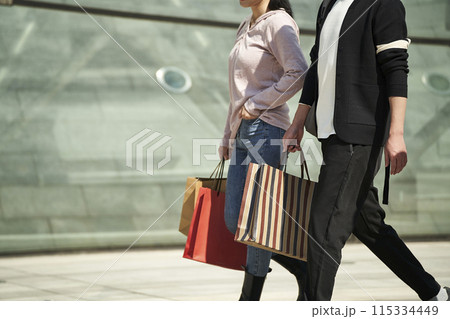 young asian couple walking on street with shopping bags in hand 115334449
