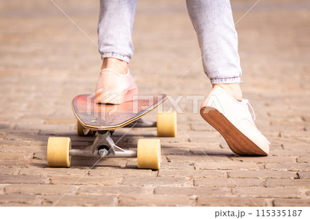 A closeup image capturing a person with pink shoes riding a skateboard on a pavement A closeup image capturing a person with pink shoes riding a skateboard on a pavement 115335187