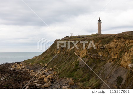 The image shows cliffs, a lighthouse, and a rocky coastline against a dusky sky The image shows cliffs, a lighthouse, and a rocky coastline against a dusky sky 115337061