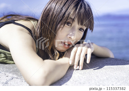 防波堤に寝転んで海を満喫する若い女性 防波堤に寝転んで海を満喫する若い女性 115337382