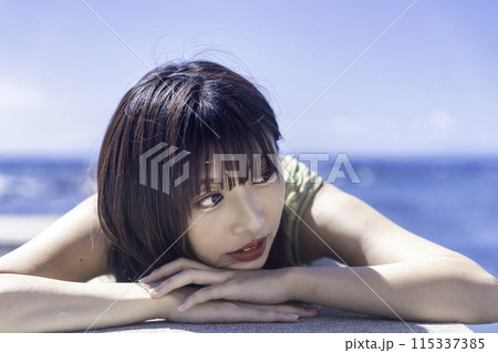 防波堤に寝転んで海を満喫する若い女性 防波堤に寝転んで海を満喫する若い女性 115337385