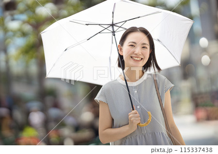 街中を日傘をさして歩く若い女性 115337438