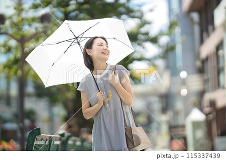 街中を日傘をさして歩く若い女性 115337439