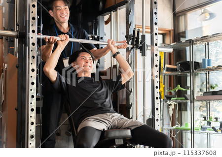ジムでパーソナルトレーニングを受ける男性とトレーナー・インストラクターの男性 115337608