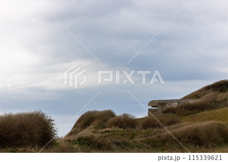 A Concrete Bunker Sits on a Dramatic Cloudy Hilltop Overlooking the Coastal Landscape 115339621