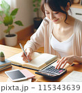 電卓を打ちながら家計簿をつけている日本人女性 115343639