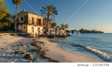 Cozy beach house by the sea at sunset, perfect for serene vacations. The setting sun casts a golden glow on the tranquil surroundings. This scenic photo captures the peaceful essence of coastal 115345748