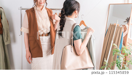 アパレルショップで鏡を見ながら女性店員にコーディネートしてもらう女性買い物客 アパレルショップで鏡を見ながら女性店員にコーディネートしてもらう女性買い物客 115345859