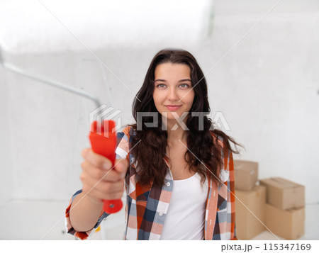 Happy Woman with Paint Roller Starting Home Improvement Task Happy Woman with Paint Roller Starting Home Improvement Task 115347169