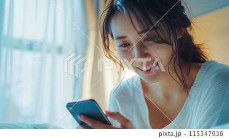 携帯電話でデジタル・コンテンツを楽しむ女性。デジタル世代のイメージ。 115347936