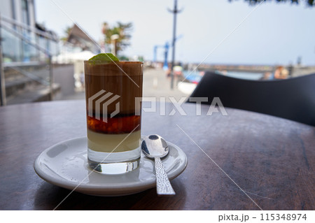 A Barraquito, canarian coffee on a table next to the sea. 115348974