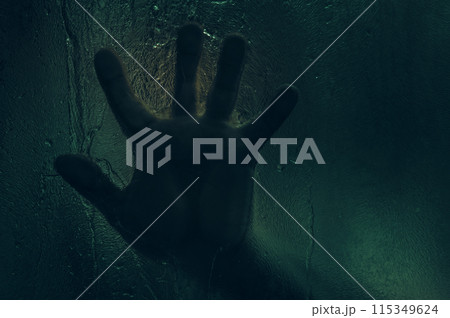 Horror scene of a man against wet glass. Hand against the background of a wet glass bathroom wall. Toned image. 115349624