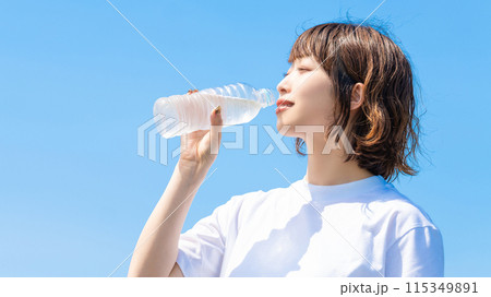 ペットボトルの水を飲む白いTシャツの女性・熱中症対策 ペットボトルの水を飲む白いTシャツの女性・熱中症対策 115349891