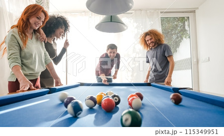 Cheerful multiethnic friends playing pool together at home 115349951