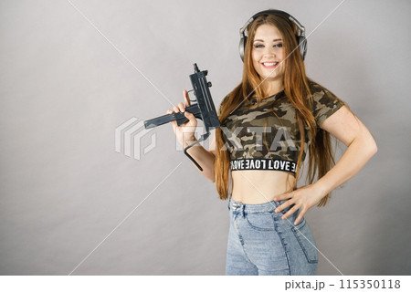 Woman wearing headphones holding gun Woman wearing headphones holding gun 115350118