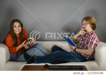 Woman playing games man reading book 115350196