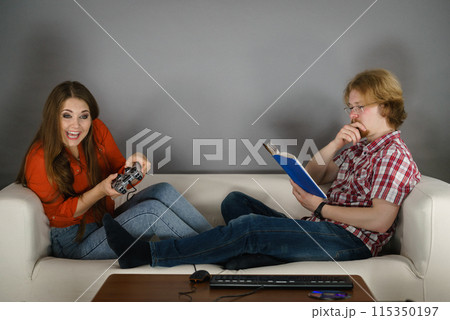 Woman playing games man reading book 115350197
