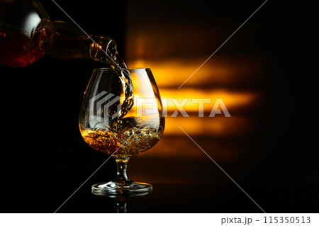 Pouring brandy from a bottle into a snifter. 115350513