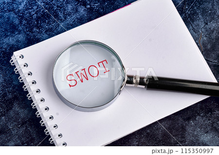 SWOT (SWOT analysis) text through a magnifying glass in a notebook on a beautiful blue heterogeneous background SWOT (SWOT analysis) text through a magnifying glass in a notebook on a beautiful blue heterogeneous background 115350997