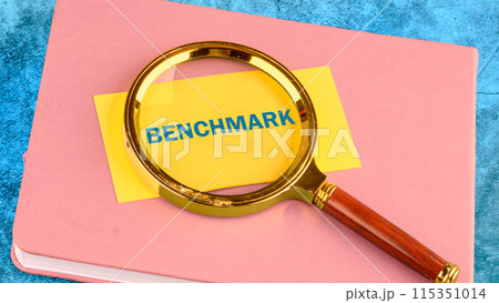 Text BENCHMARK on a yellow business card with a magnifying glass on top Text BENCHMARK on a yellow business card with a magnifying glass on top 115351014