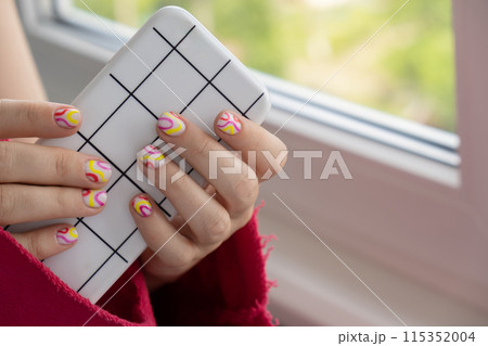 Stylish summer colorful nails female manicured hands holding mobile phone. Closeup of manicured nails of woman hand. Summer style of nail design concept. Beauty Stylish summer colorful nails female manicured hands holding mobile phone. Closeup of manicured nails of woman hand. Summer style of nail design concept. Beauty 115352004