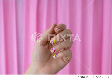 Pastel softness colorful manicured nails on pink background. Woman showing her new summer manicure in colors of pastel palette. Simplicity decor fresh spring vibes earth-colored neutral tones 115352005