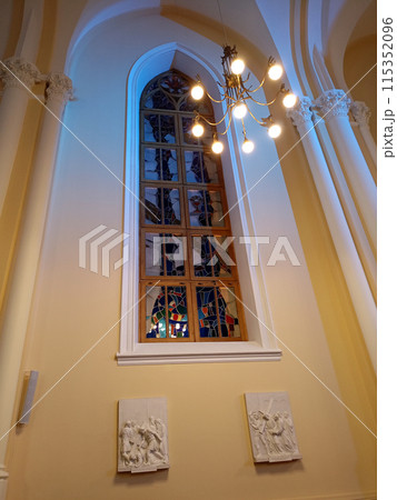 Window with colored stained glass and a burning chandelier in the Cathedral Window with colored stained glass and a burning chandelier in the Cathedral 115352096
